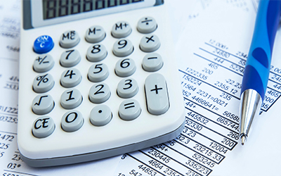 A calculator sitting on a paper with financial numbers on it and a pen laying beside it