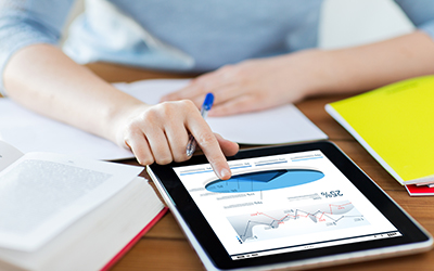 Close-up of someone working with pie charts and bar graphs on a tablet